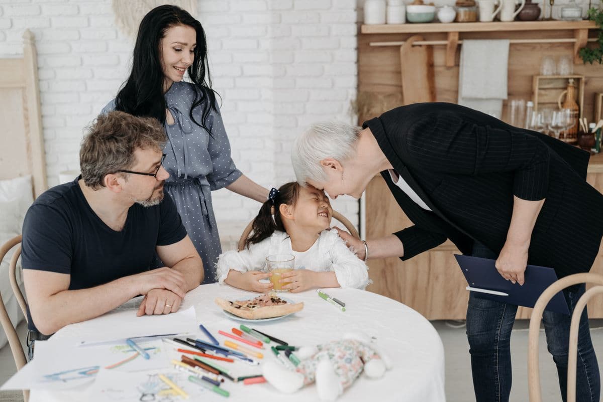 A caseworker meeting with a family and their young daughter at the kitchen table